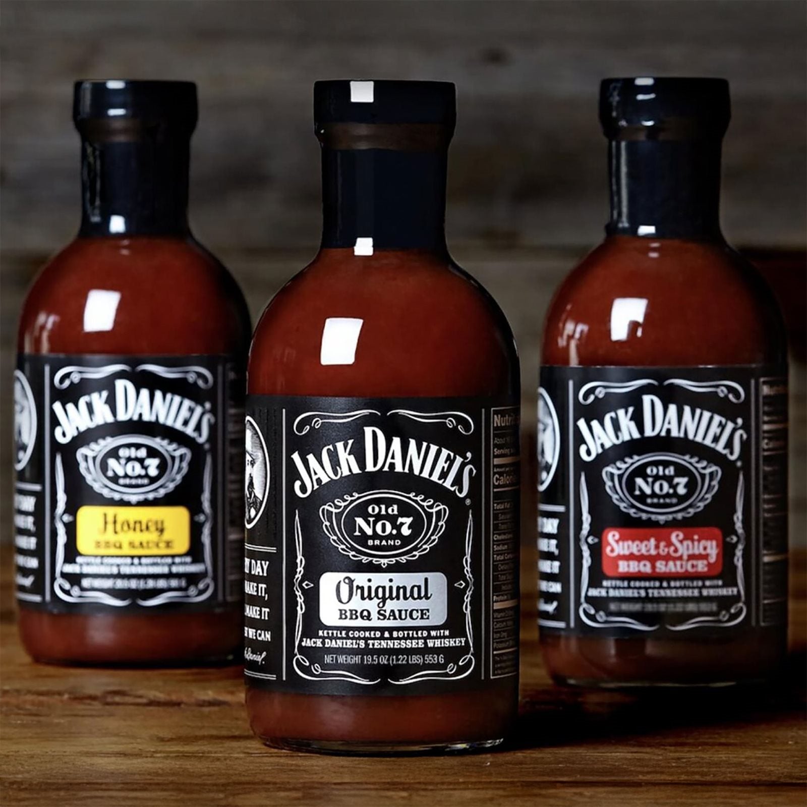 Tre flasker med Jack Daniel's BBQ-saus står utstilt på tre, med de klassiske smakene Jack Daniel's BBQ Original (473 ml), Honey og Sweet & Spicy - alle laget med ekte Tennessee Whiskey.