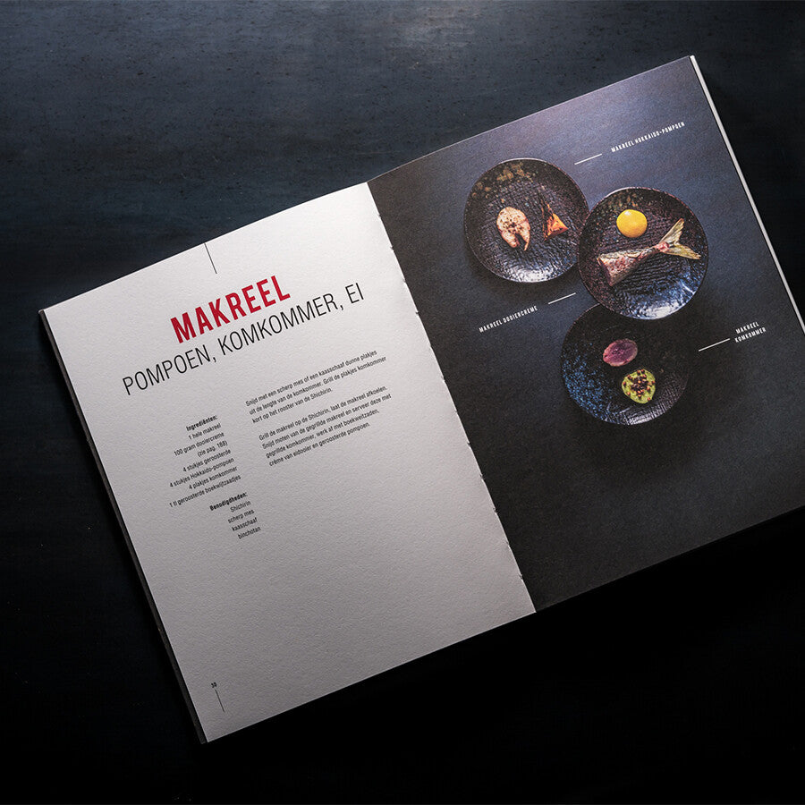 En åpen meny viser "Makreel", inspirert av japanske grillsmaker fra kokeboken Japanese Grill YAKINIKU, Shichirin Kokebok, med beskrivelser til venstre og tre nederlandskmerkede retter i mørke skåler til høyre.