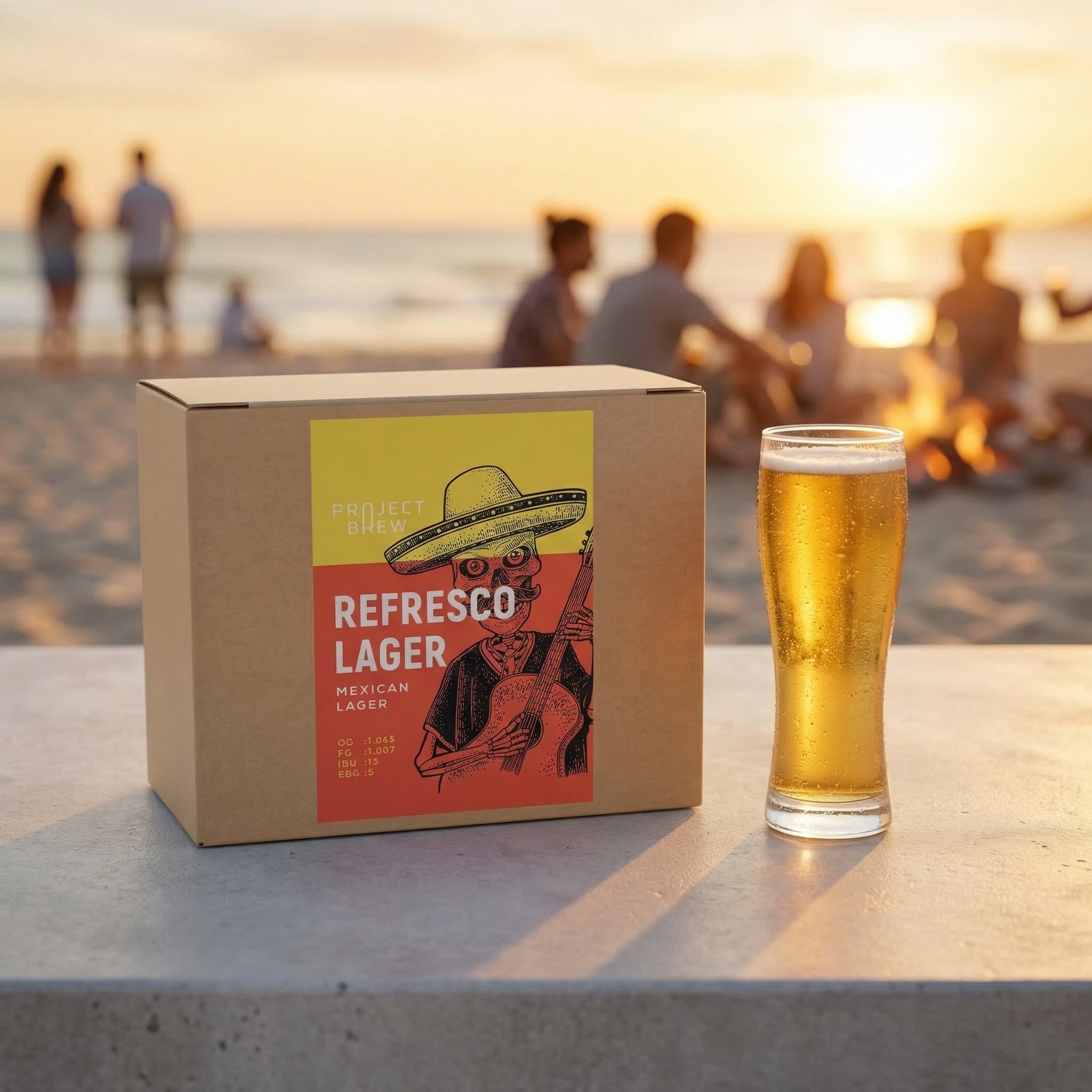 Et glass pils og en boks merket Refresco Mexican Lager - allgrain ølsett står på et bord nær stranden i solnedgangen, med folk og bål i bakgrunnen.