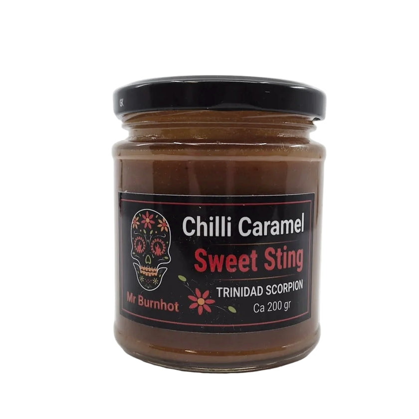 En krukke med «Sweet Sting Spicy Caramel» | Mr Burnhot, 200 gram, med svart lokk og et hodeskalle-motiv på etiketten. Denne håndlagde karamellen byr på en uimotståelig blanding av søt karamell og intens styrke fra ekte Trinidad Scorpion-chili – perfekt for alle som ønsker en dristig og krydret karamellopplevelse.