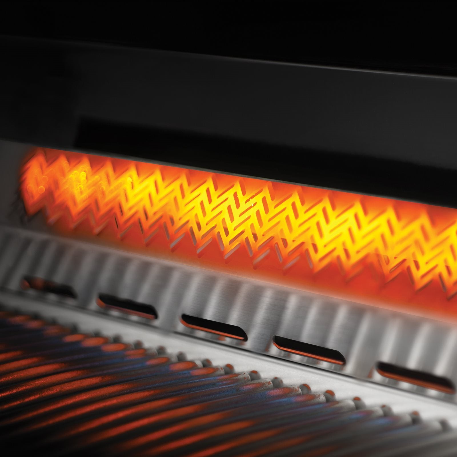 Nærbilde av en aktiv infrarød brenner som gløder oransje over en grillrist av metall på Napoleon Built-in 700 Series 32" sort (Bestillingsvare), perfekt for utekjøkkenet ditt.