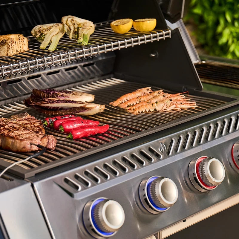 Nærbilde av Napoleon Prestige PRO™ 500 Connected i rustfritt stål/svart, der det grilles reker, biff, paprika og radicchio – med artisjokker og sitroner ovenpå. Oppnå perfekt steking med den kraftige infrarøde SIZZLE ZONE.