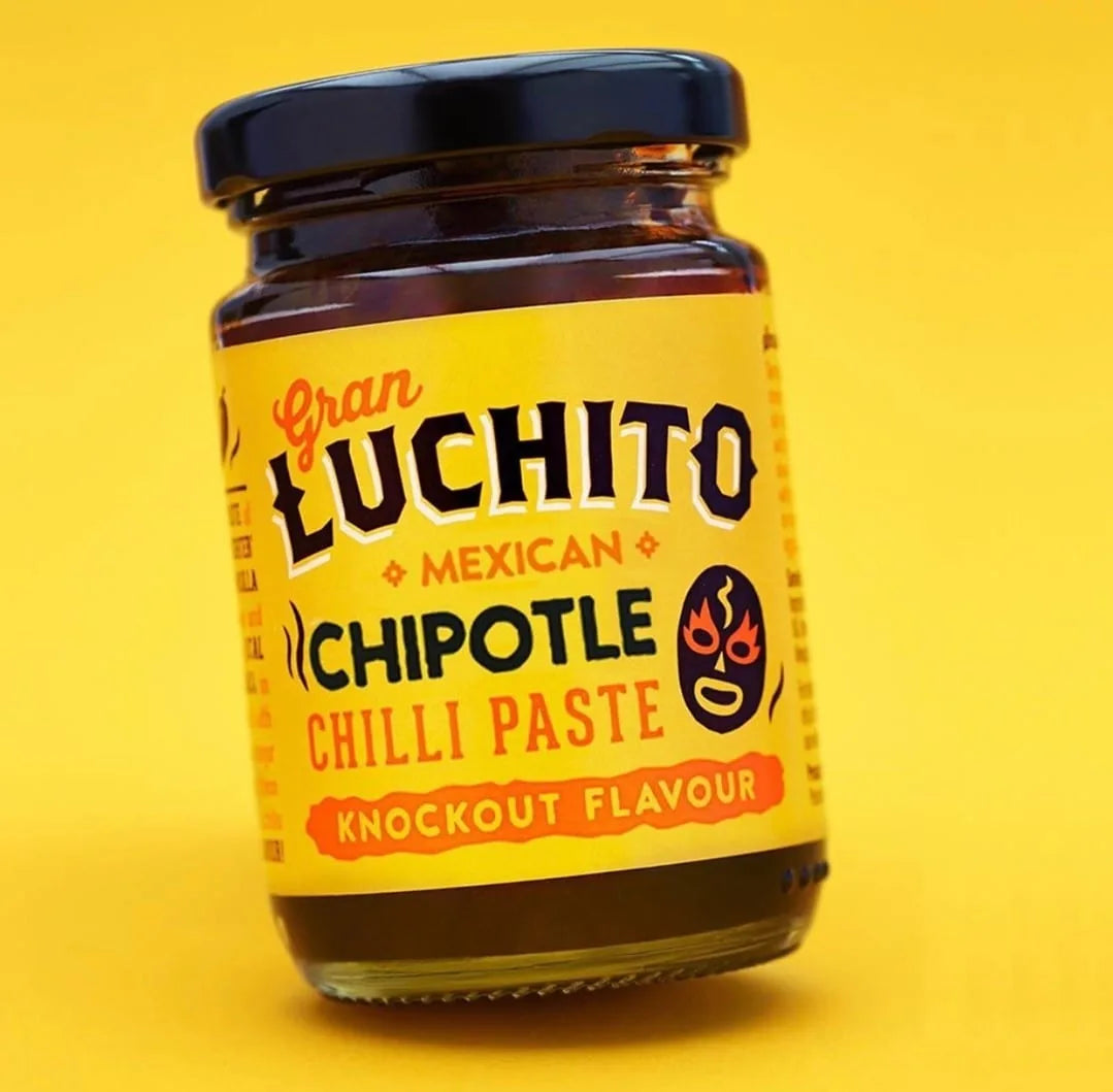 Et glass med Gran Luchito Smoky Chili Paste 100 g med Knockout Flavour-etikett mot en kraftig gul bakgrunn.
