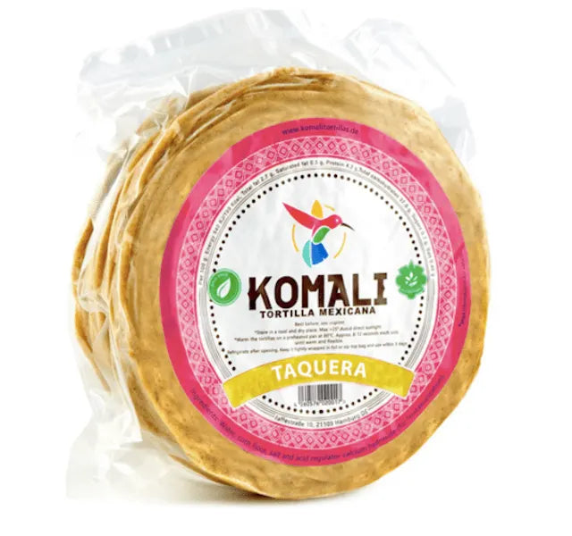En klar plastpakke med Komali Maistortilla 12 cm, 25stk, med fargerikt design og næringsinformasjon - laget av nixtamalisert mais for autentiske meksikanske tortillaer klare til servering.