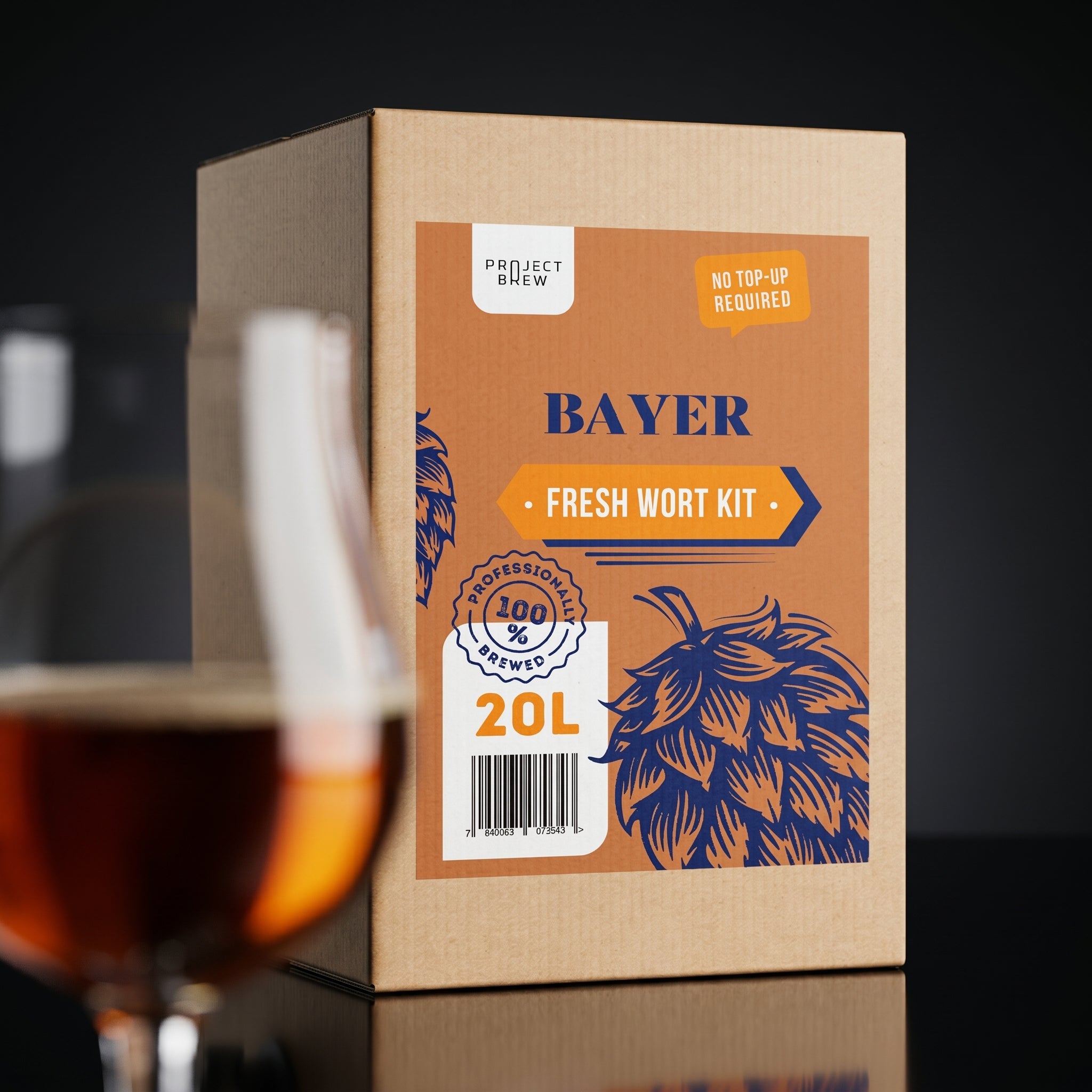 Ved siden av et glass med mørkt, ravfarget øl står en 20 liters pappeske merket "Bayer - 20L Fresh Wort Kit". Emballasjen viser humleillustrasjoner og bryggesertifisering, designet for hjemmebryggere.