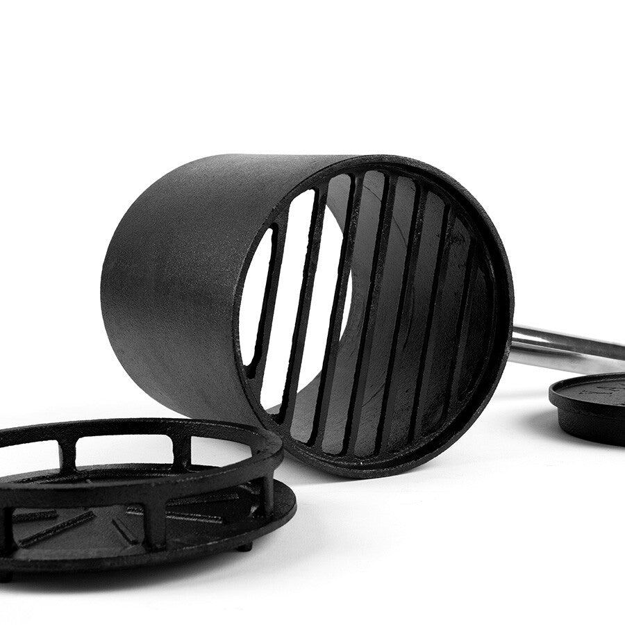 En YAKINIKU Binchopan for opptenning og slukking av kull, formet som en svart metallsylinder med vertikale streker, ligger på siden ved siden av to flate, runde metallstykker på hvit bakgrunn.