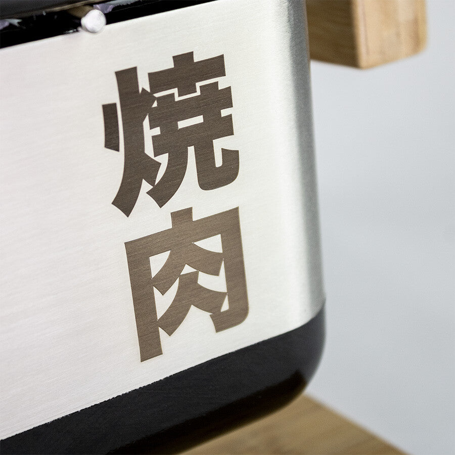 Nærbilde av en metalloverflate med japanske kanji-tegn 焼肉, sannsynligvis en del av YAKINIKU MEDIUM Rectangular Shichirin PRO | Konro & Yakitori Grill.