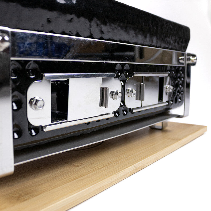 Nærbilde av et chafing dish-lokk i metall og svart med låseklips, hvilende på tre, som minner om den elegante stilen til YAKINIKU Rectangular Shichirin | Konro & Yakitori Grill.