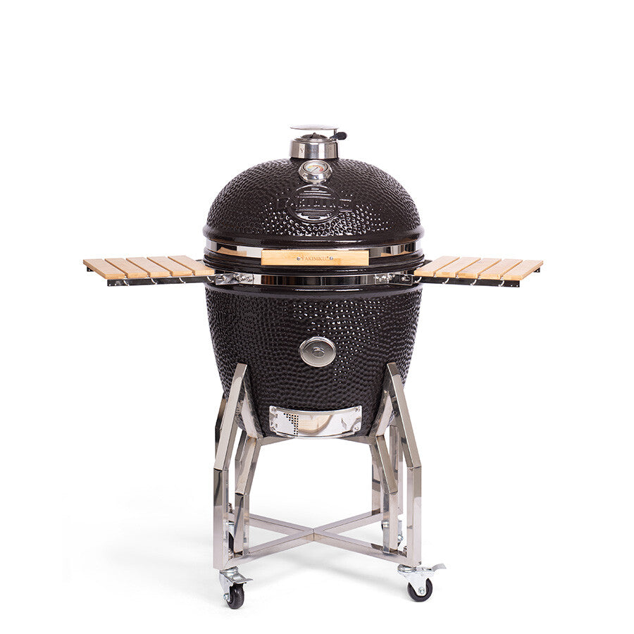 YAKINIKU XLARGE Kamado Complete er en svart keramisk grill i Kamado-stil på et metallstativ med hjul, med temperaturmåler, sidehyller i tre og nedre ventilasjon for profesjonell grilling.