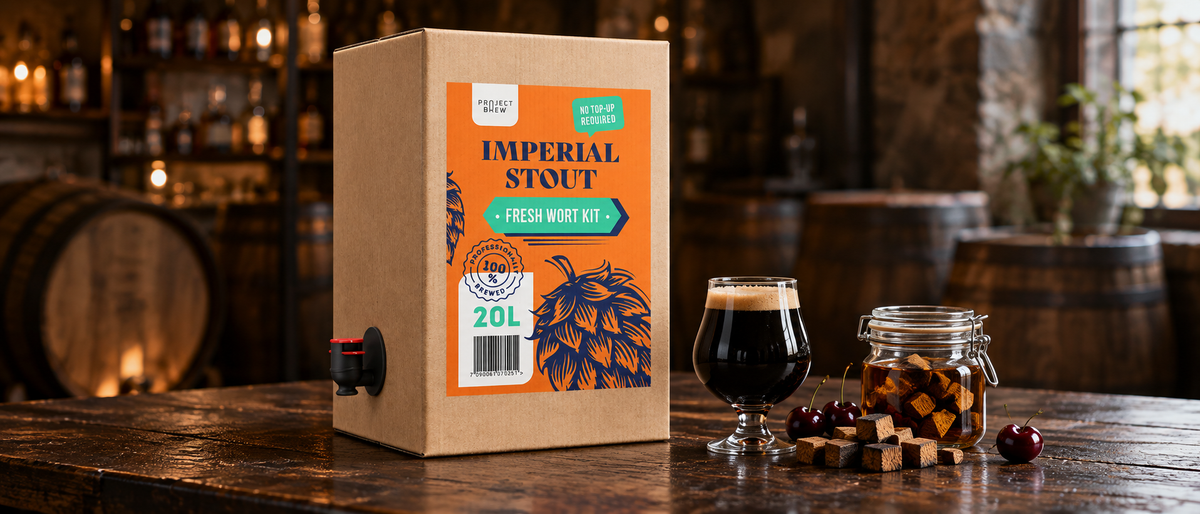 Imperial Stout 20L Fresh Wort Kit ved siden av et glass mørk stout, kirsebær og et glass med eikekuber, foran eikefat