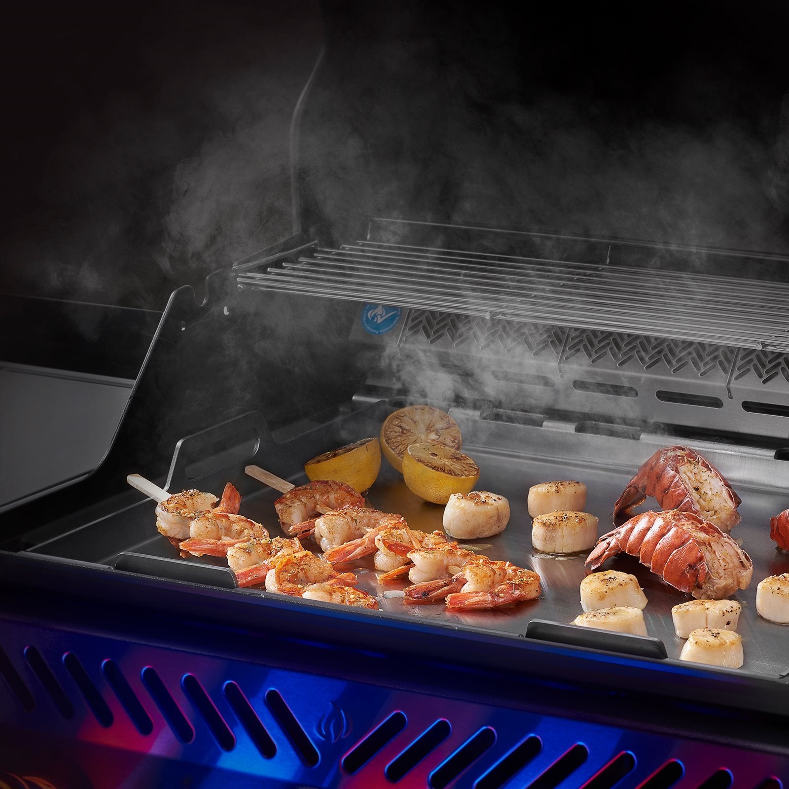 Rekespyd, kamskjell, hummerhaler og halverte sitroner grilles på en Napoleon Plancha til 425 grader med oppstigende damp.