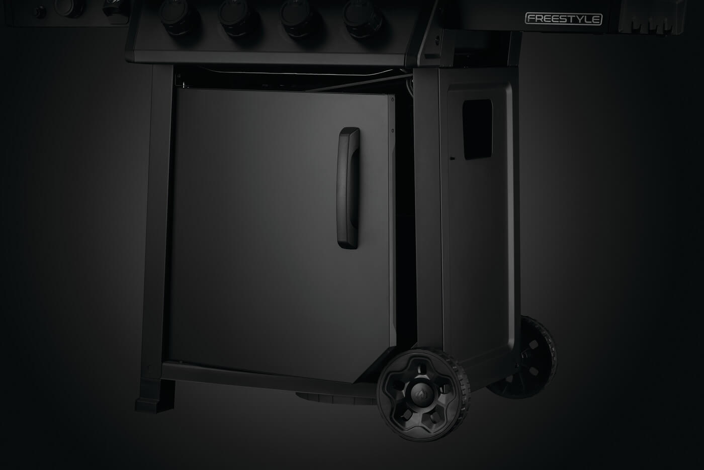 Nærbilde av den nedre delen av en Napoleon Phantom Freestyle 425 gassgrill i svart, med skapdør, hjul, toppmonterte betjeningsknapper og slitesterke detaljer i rustfritt stål av høy kvalitet.