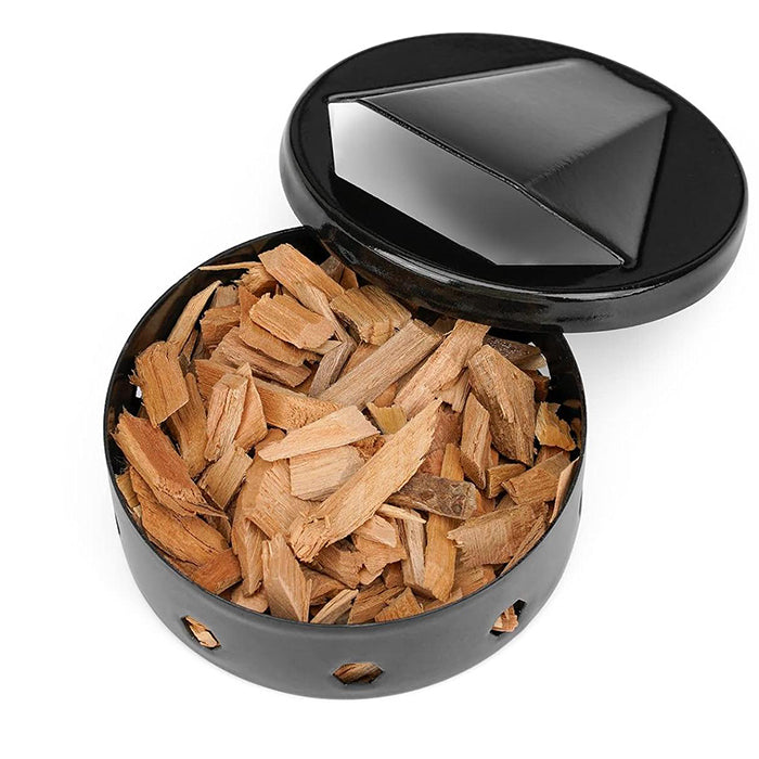 Rund Røykboks til Grill i sort metall med ventilert lokk, fylt med treflis. Perfekt for å tilføre røyksmak til maten. Produktet er avbildet isolert mot hvit bakgrunn.