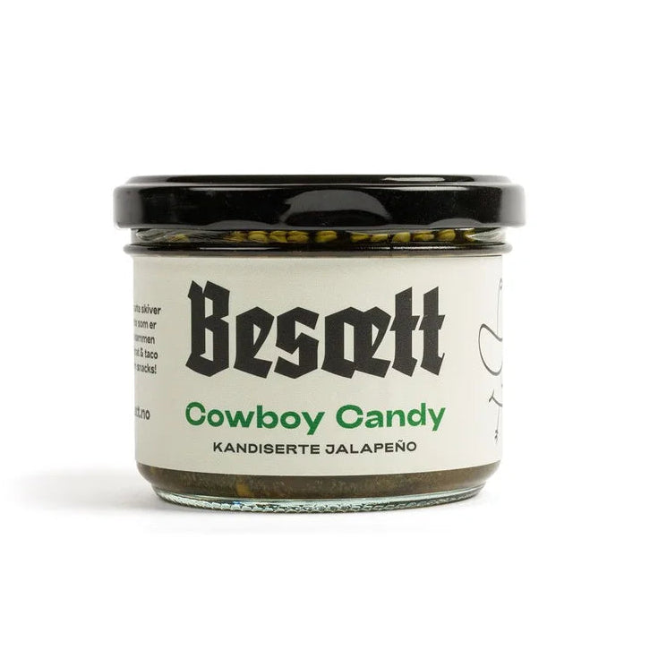 En glasskrukke med etiketten «Cowboy Candy – Sprø, Sterk & Søt | Besætt», som inneholder søt, sterk chili med kandiserte jalapeño, et svart lokk og en elegant hvit etikett.