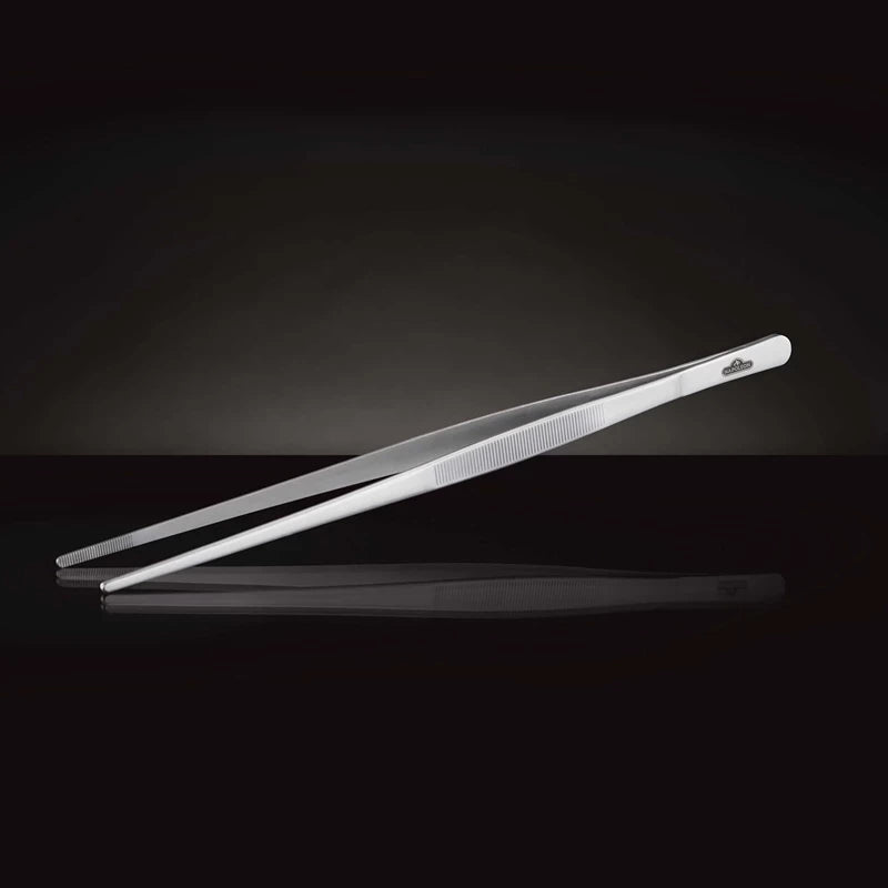 Napoleon matpinsett i rustfritt stål med teksturert grep vises på en reflekterende svart overflate mot en mørk bakgrunn.