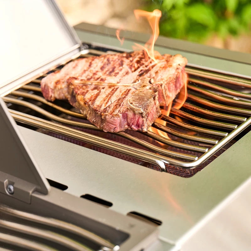 En biff med grillmønster stekes på en Napoleon Prestige PRO™ 500 Connected, rustfritt stål/svart (bestillingsvare), mens små flammer fra den kraftige infrarøde SIZZLE ZONE flimrer nær kanten av kjøttet.