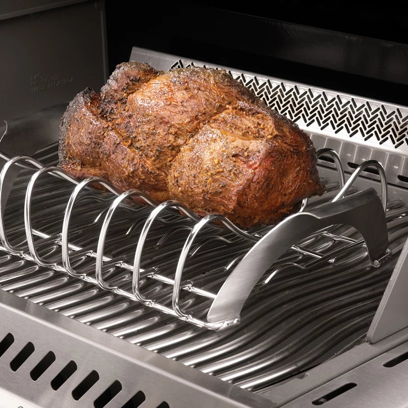 En stekt stek hviler på et Napoleon PRO sparerib- og stekestativ i grillen, med synlige grillrister og bakre varmediffusor - essensielt grilltilbehør for et perfekt resultat.