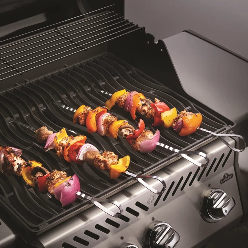 Fire Napoleon Shashlik grillspyd med grillede grønnsaker og sopp tilberedes på en åpen, svart gassgrill, og hvert spyd er laget av rustfritt stål for varig holdbarhet.