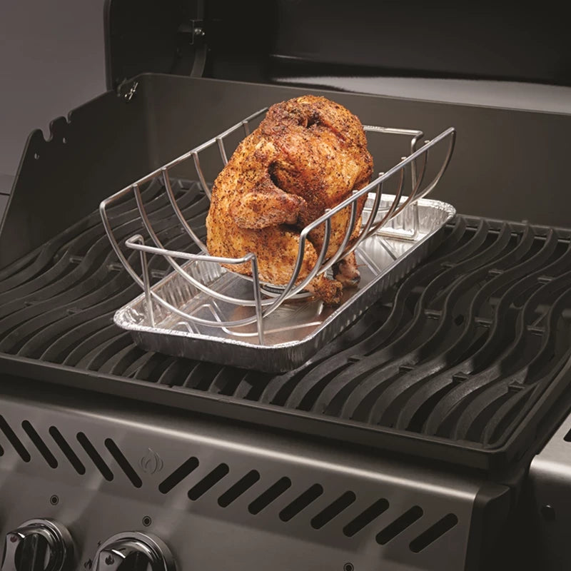 En hel, krydret kylling hviler på Napoleon Steke- og kyllingstativ over et foliebrett inne i en grill med lokket åpent.