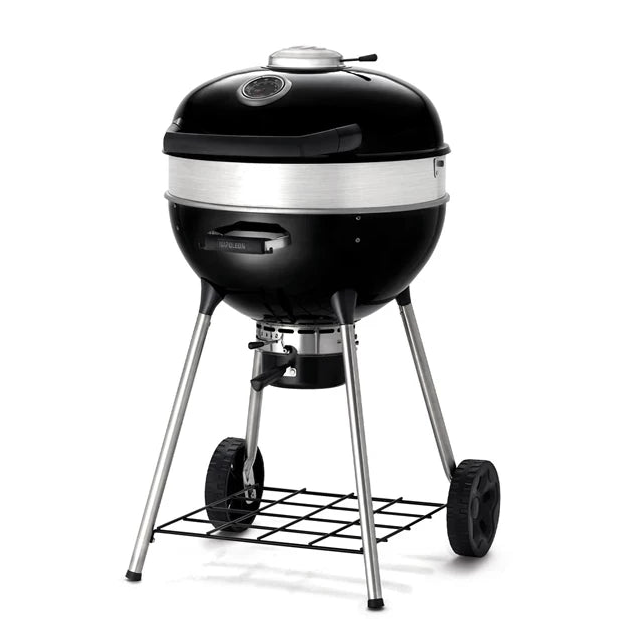 Napoleon PRO22 Kulegrill 57 cm er en svart kullgrill med kuppelformet lokk, innebygd termometer, ventilasjon, to hjul og et nedre oppbevaringsstativ av ståltråd. Fotografert på hvit bakgrunn.