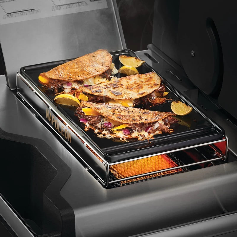 To brettede tortillas med kjøtt, løk og pålegg freser på en Napoleon Stekeplate til SIZZLE ZONE, stor, med appelsinbåter ved siden av.