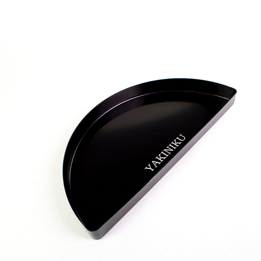 Den svarte, halvsirkelformede YAKINIKU Halvmåne Dryppfat XLARGE / LARGE, med "YAKINIKU" i hvitt på bunnen, er ideell for indirekte grilling i kamadoen din og vises på hvit bakgrunn.